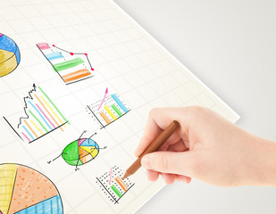 Business person drawing colorful graphs and icons on paper