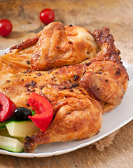 small grilled chicken with vegetables on a white dish