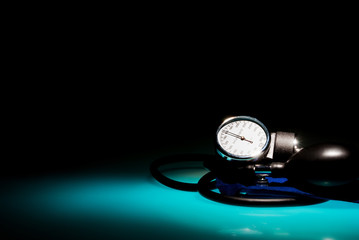 Sphygmomanometer on blue, reflective table and black background