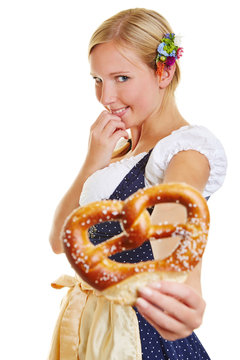 Woman in dirndl offering pretzel