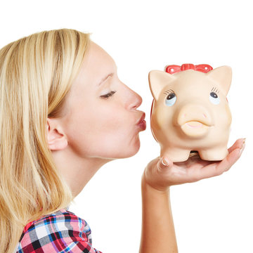 Blond woman kissing piggy bank