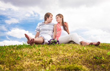 Fototapeta premium Beautiful pregnant woman sitting on lawn with husband