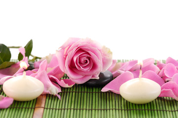 Rose with petals and candle on green mat