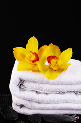 Obraz na płótnie Canvas towel and yellow orchids on a black background