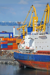 Fototapeta premium Container stack and cargo ship under crane bridge