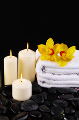 Fototapeta na wymiar towel and yellow orchids on a black background