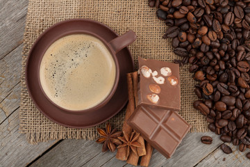 Coffee cup with spices and chocolate on wooden table texture