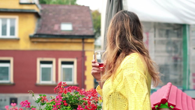Sad, pensive beautiful woman drinking wine on balcony