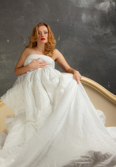 Blonde naked in bed on a gray background.