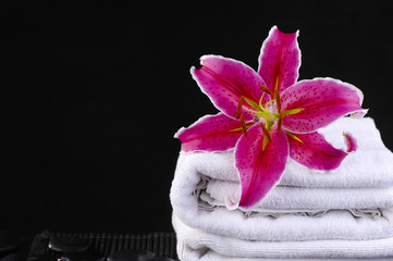 Obraz na płótnie Canvas Lily pink flower on towel with pebbles on mat