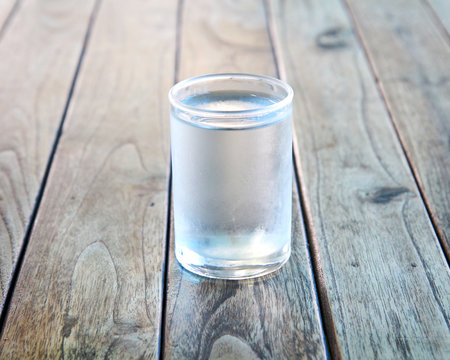 Glass of water on a wooden floor.