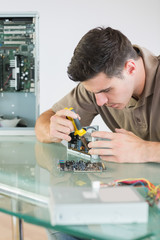 Handsome focused computer engineer repairing hardware with plier