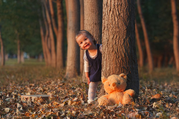 Cute little girl is playing hide and seek with her teddy bear