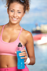 Fitness brunette drinking water and cooling off after running at