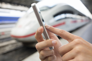 Close up of hands woman using her cell phone at a station platfo