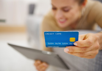 Closeup on credit card in hand of young woman laying on couch