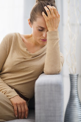 Portrait of stressed young housewife sitting on couch
