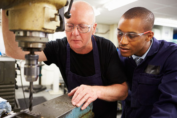 Engineer Teaching Apprentice To Use Milling Machine - Powered by Adobe