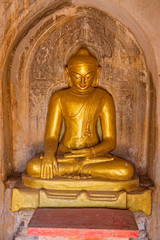 Old renovated sculpture of a golden seated Buddha