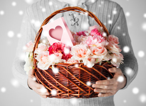 man holding basket full of flowers and postcard