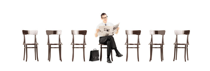 Young businessman sitting on a chair and reading a newspaper