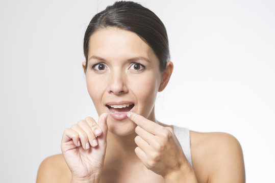 Frau benutzt Zahnseide um ihre Zähne zu pflegen