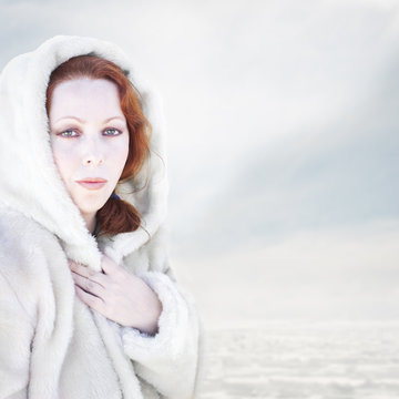 Mujer con abrigo blanco en la nieve.