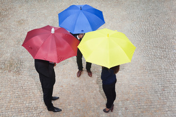 Business people hidden under colorful umbrellas