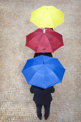 Business people hidden under colorful umbrellas, lined up