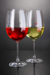 Red and white wine in glasses on grey background