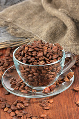 Coffee beans in cup on wooden background
