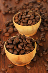 Coffee beans in bowls on wooden background