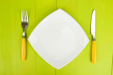 Plate and cutlery on wooden table close-up