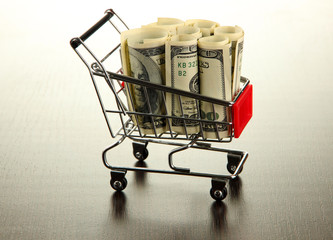 Shopping trolley with dollars, on dark background