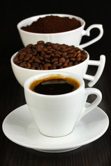 Different types of coffee in three cups on wooden table