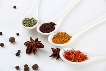 Assortment of spices in  white spoons, isolated on white