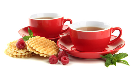 Fototapeta premium Cups of tea with cookies and raspberries isolated on white