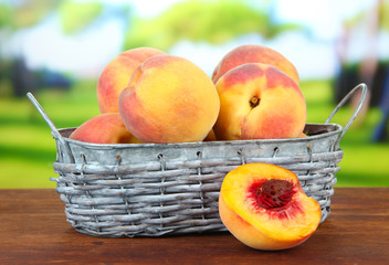 Ripe sweet peaches in wicker basket, on bright background