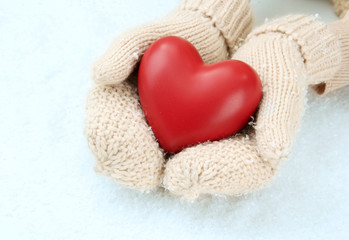 Female hands in mittens with red heart, close-up
