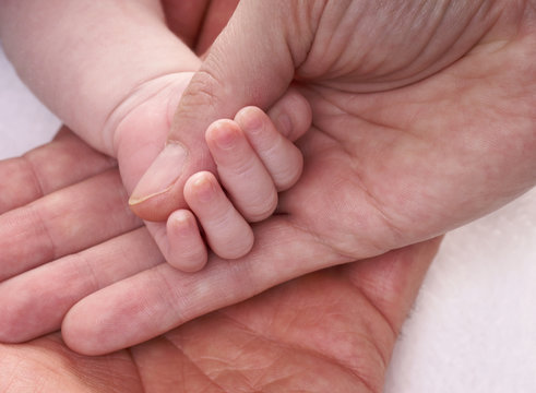 Hände halten eine Babyhand