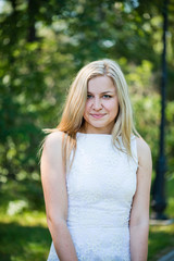 Beautiful young blond woman in a white dress outdoors