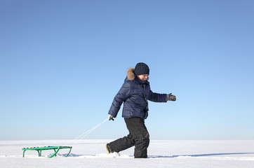 Fototapeta na wymiar boy with sled on sky background