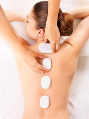 Obraz na płótnie Canvas Woman having hot stone massage in spa salon.