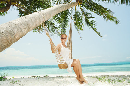 view of nice young lady swinging  in hummock on tropical beach