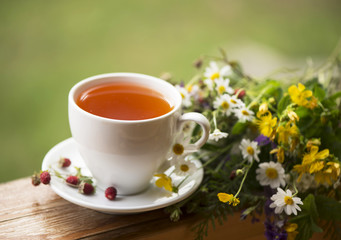 cup of aromatic tea, some berries of wild strawberry, bouquet of