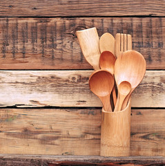 Kitchen wooden utensils in retro bucket over wooden background