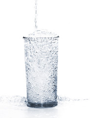 pouring water into the glass isolated on a white background