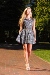 Fashion young woman in summer dress relaxing in park