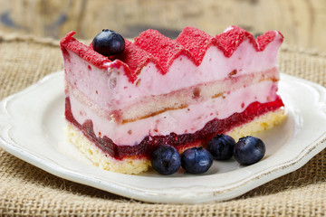 Pink layer cake decorated with fresh fruits on wooden table. Sel