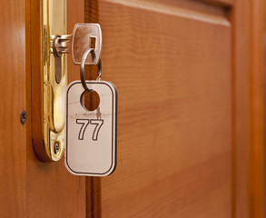 Door handles on wood wing of door and key in keyhole with number